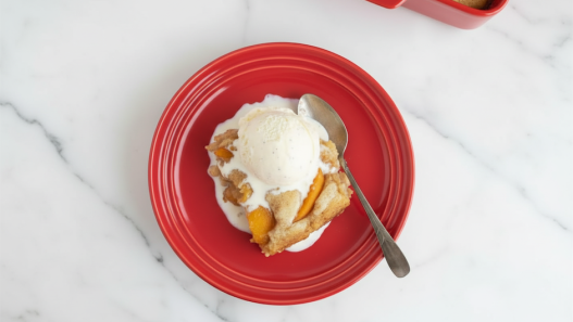 peach cobbler on red plate with icecream